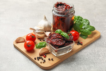 Delicious sun dried tomatoes, fresh vegetables, basil and garlic on light grey table