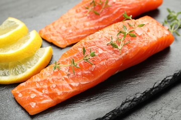 Seafood. Pieces of salmon fillet, thyme and lemon slices on table, closeup