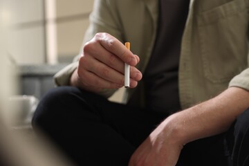 Man smoking cigarette on blurred background, closeup