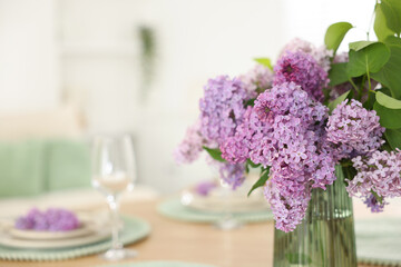 Fototapeta na wymiar Beautiful lilac flowers in vase on table, closeup. Space for text