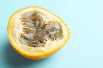 Piece of ripe yellow passion fruit on light blue background, closeup. Space for text