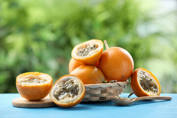 Ripe passion fruits and seeds on light blue wooden table outdoors