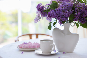 Bouquet of beautiful lilac flowers, coffee and dessert on white table indoors. Space for text