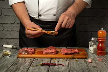 A chef prepares raw meat by carefully sprinkling seasoning from a spoon, showcasing culinary skills. The kitchen is well-lit, enhancing the focus on the fresh ingredients