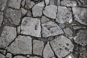 Top Down View Of An Old Pavement Made Of Large, Irregularly Shaped Light Grey Natural Stones. Historic Cobblestone Road Or Pathway Texture Background.