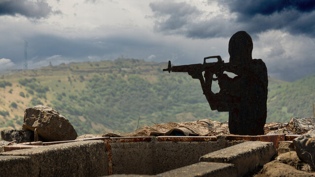 Metal cut-out of the silhouette of a soldier atop Mount Bental overlooking Syria in the Golan Heights of Israel with dark storm clouds - Powered by Adobe