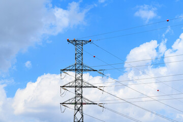 Large tower with high-voltage electric lines and a partly cloudy sky