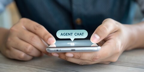 Hands hold a modern smartphone showcasing a digital chat bubble that reads 'Agent Chat', personifying seamless customer service. 