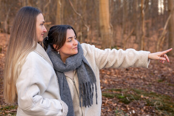 Two women in the forest. Woman pointing at the scenery. People in nature.
