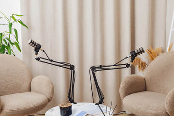 Cozy podcast setup with microphones and chairs in a modern indoor space for engaging interviews