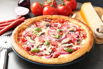 Tasty pizza with smoked sausages, ingredients and cutter on gray table, closeup