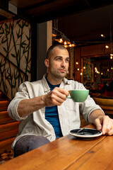 Thoughtful man savoring a warm cup of coffee in a stylish cafe, enjoying a peaceful moment of reflection amidst a busy day