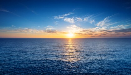 Naklejka premium sunset over the vast ocean with a blue sky and calm sea surface