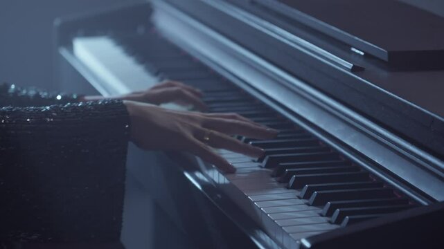 Two hands play piano music on piano in dark smoky room. Young pianist plays the piano with grace. Elegant female musician. Close-up in 4K, UHD