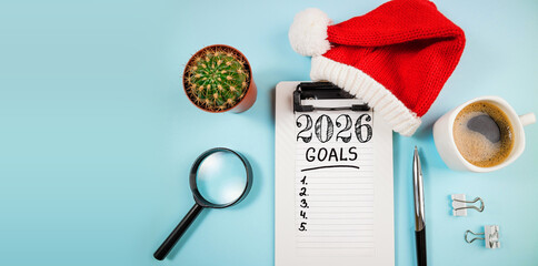 New year resolutions 2026 on desk. 2026 goals list with notebook, coffee cup, plant on blue table. Resolutions, plan, goals, action, checklist, idea concept. New Year 2026 resolutions, copy space