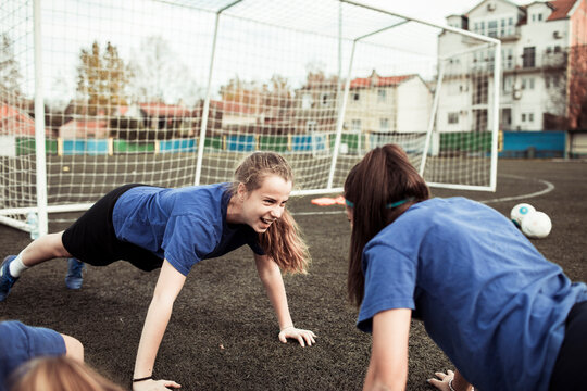 Teen girls doing push ups on soccer field during team practice - Powered by Adobe