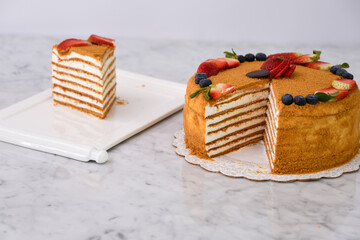 Layered Medovik Honey Cake with strawberry and blueberry slice isolated on grey background closeup...