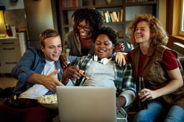 Young and diverse group of friends watching a movie on laptop in the living room on the couch