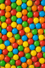Fototapeta premium Colorful chocolate candies in red, yellow, green, blue, and orange arranged in a seamless pattern. Fun and vibrant background for sweets, parties, or advertising.