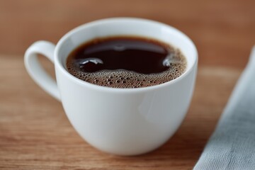 White cup of freshly brewed black coffee on wooden surface