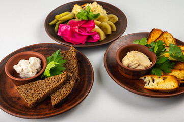 Traditional Eastern European cuisine served on rustic clay plates. A variety of homemade dishes including meat, potatoes, pancakes, dumplings and grilled vegetables, on a rustic background, top view.