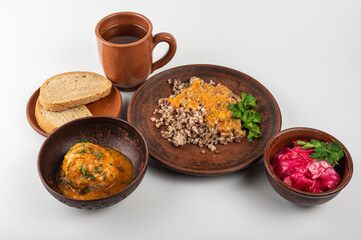 Traditional buckwheat porridge with caramelized onions on a rustic plate. A hearty, nutritious and aromatic dish, popular in Eastern European cuisine, on a clay plate, on a white background