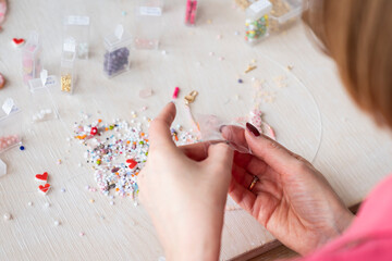 A creative girl is engaged in beadwork. Hobby and small business concept	