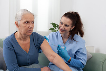 Fototapeta premium Nurse or doctor holding syringe, preparing injection of vaccine or medication for elderly patient at home or clinic. Medical care, treatment, and prevention concept