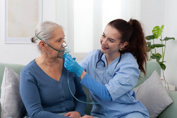 Nurse or doctor assists elderly woman using a respirator oxygen during home or clinic treatment....