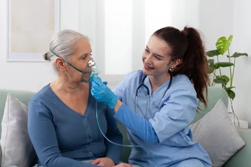 Nurse or doctor assists elderly woman using a respirator oxygen during home or clinic treatment. Respiratory care, medical support, and senior health care assistance © amedeoemaja