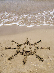 Sol sonriente dibujado en la arena de la playa