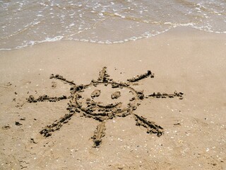 Sol sonriente dibujado en la arena de la playa