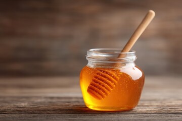 Glass Jar Filled with Golden Honey and Wooden Dipper on Rustic Wooden Surface