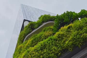 Modern architectural structure with lush greenery in urban setting captures sustainable design principles during cloudy day