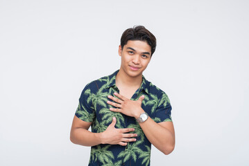 A young Southeast Asian man placing his hand on his chest with a warm expression, as if introducing himself. Isolated on a light background.