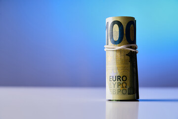 A 100 euro bill is wrapped in a string. Concept of security and protection, as the bill is tied up to prevent it from being lost or stolen. The blue background adds a calming
