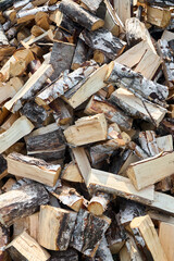 Stack of birch firewood with hand chopping block. Chopped firewood for winter. Lot of firewood - harvesting wood for heating the house. Horizontal photo. Chopped firewood background and texture 16x9.