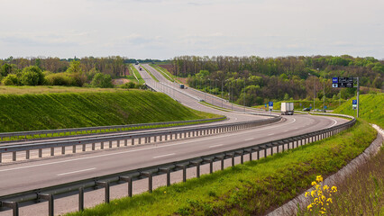 A wide highway stretches across the countryside, carrying vehicles through a beautiful landscape.