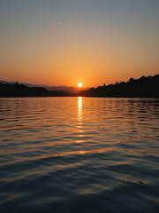 Naklejka premium Sunset reflected in water with ripples
