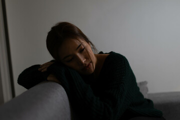 A woman stands alone by a window, lost in contemplation and sadness, reflecting emotional pain,...