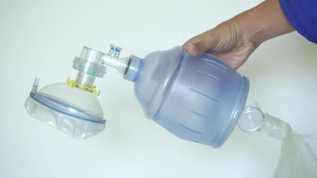 Hand holding an Ambu bag for providing respiratory assistance.