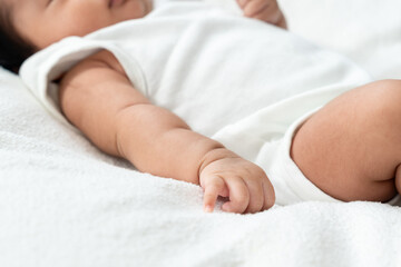 baby arm resting on soft white surface with index finger slightly extended. Gentle skin folds and natural curve of finger reflect stillness, innocence, growth, and early exploration.