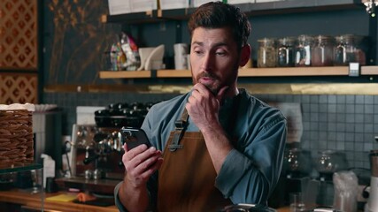 Disappointed Caucasian man barista worker looking screen mobile phone in cafe frustrated guy waiter holding smartphone employee problem business fail online cafeteria male bankruptcy difficulty tech