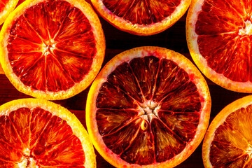 Red blood halved oranges close up on a wood background. Top view. Flat lay of fresh orange citrus...