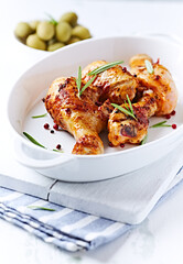 Spicy Chicken Drumsticks with fresh herbs. White wooden background