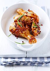 Spicy Chicken Drumsticks with fresh herbs. White wooden background