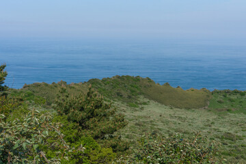 Seongsan Ilchulbong volcanic landscape, natural photography, green and blue colors, tranquil coastal view, Jeju, South Korea, no person