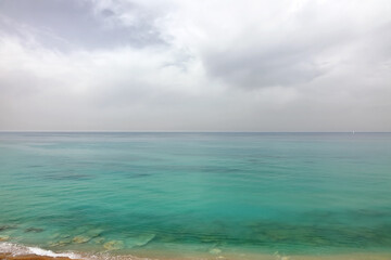 Obraz premium Panoramic view of the Mediterranean Sea with impressive emerald water against a stormy sky from a high sandy shore