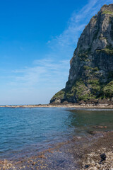 Seongsan Ilchulbong volcanic cliff, vibrant blue sky, coastal landscape, Jeju, South Korea