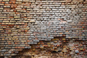 A large wall made of old bricks with dents, cracks and irregularities.